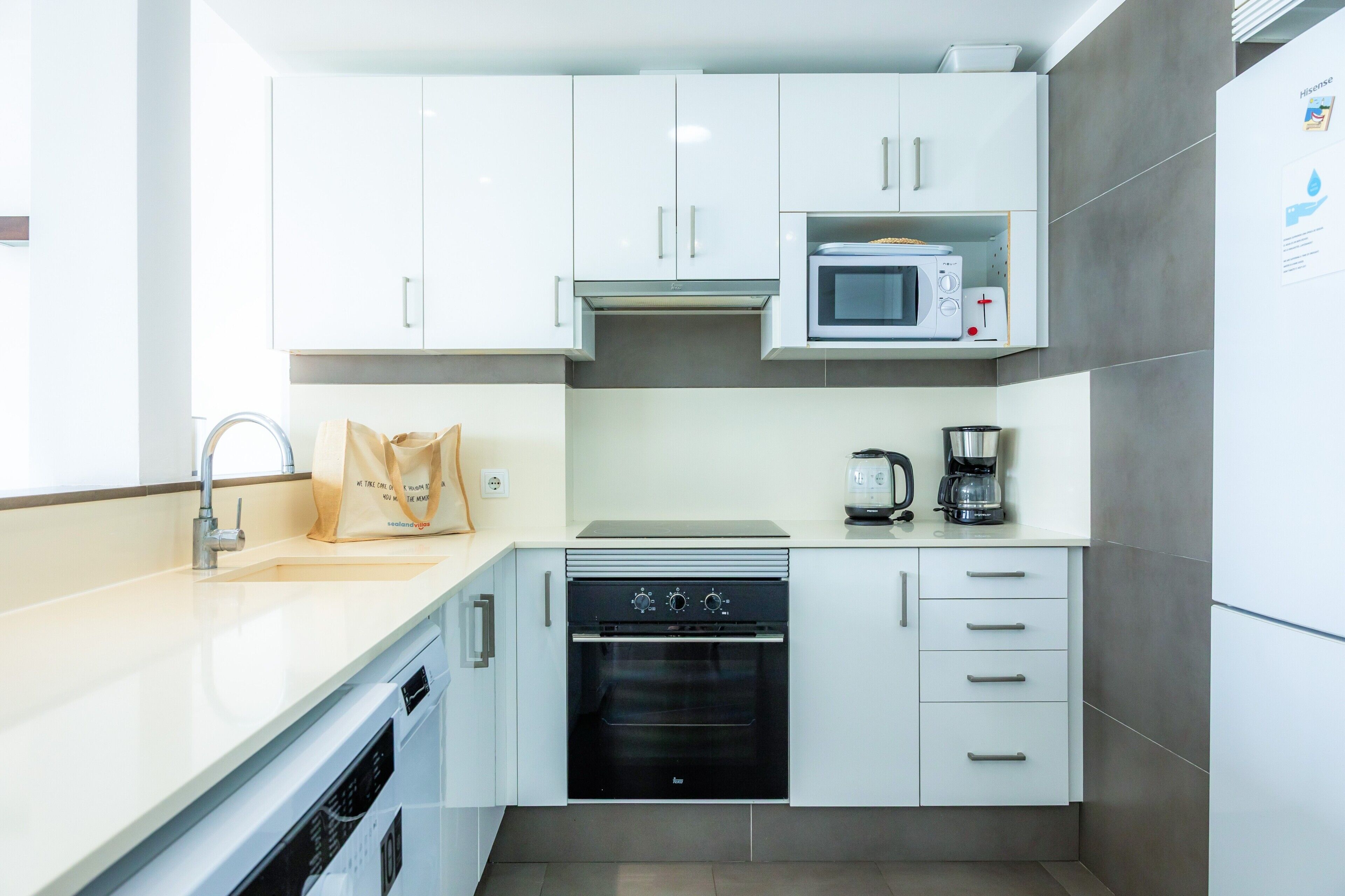 A modern kitchen with white cabinets, a microwave, a coffee maker, and a dishwasher.
