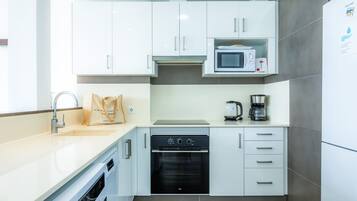 A modern kitchen with white cabinets, a microwave, a coffee maker, and a dishwasher.