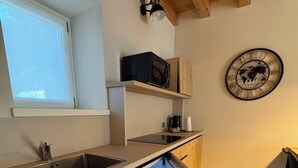 A compact kitchen with wooden cabinets, a built-in microwave, and a refrigerator with a water dispenser.
