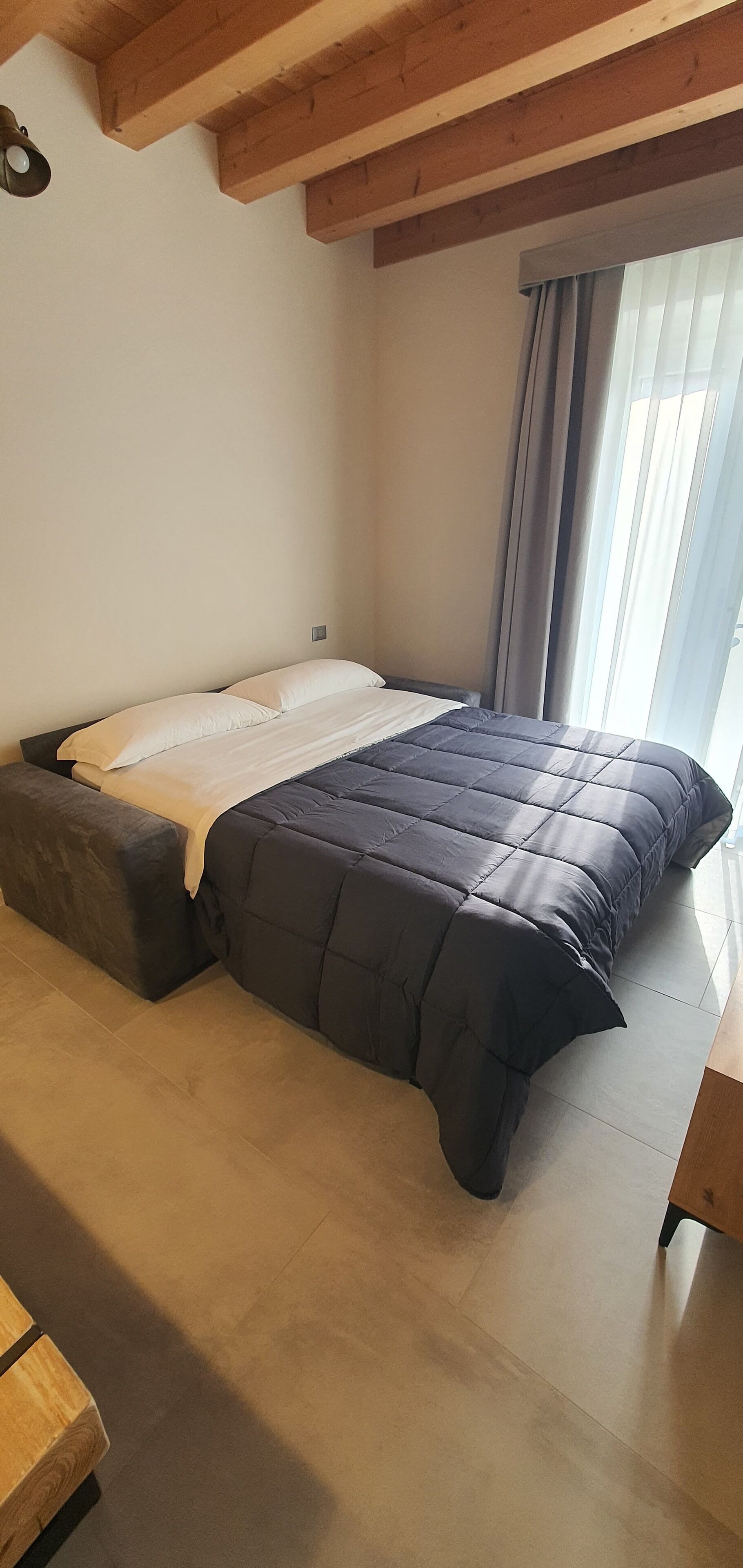 A bedroom with a bed, a wooden bench, and a window with curtains.
