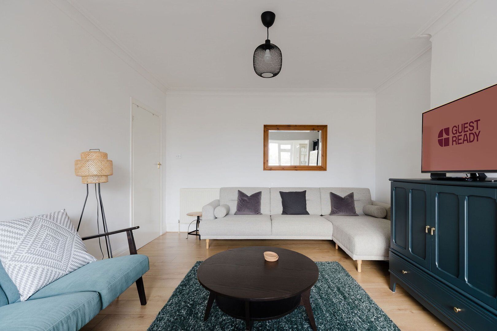 En moderne stue med sofa, sofabord, fjernsyn og skab.