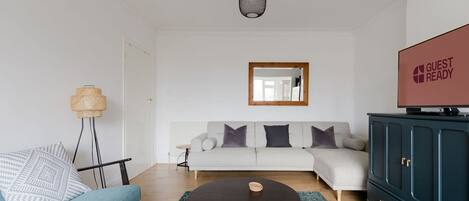 En moderne stue med sofa, sofabord, fjernsyn og skab.