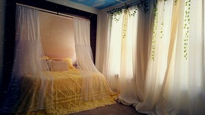 Una camera da letto con un letto a baldacchino, tende bianche con foglie verdi e un soffitto stellato.