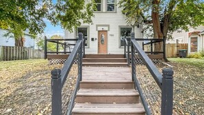 Una casa a due piani con un portico e una scala che conduce all'ingresso.