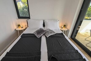 Ein Bett mit einer schwarz-weißen Steude, zwei Kissen und einem kleinen Nachttisch mit einer Pflanze.