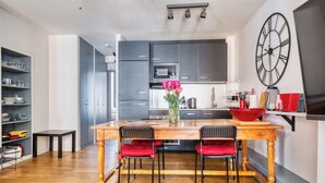 Eine moderne Küche mit dunklen Schränken, einem Holztisch und roten Stühlen.