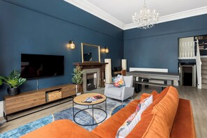 Una sala de estar moderna con una pared azul, una chimenea, un televisor, un sofá y una escalera.