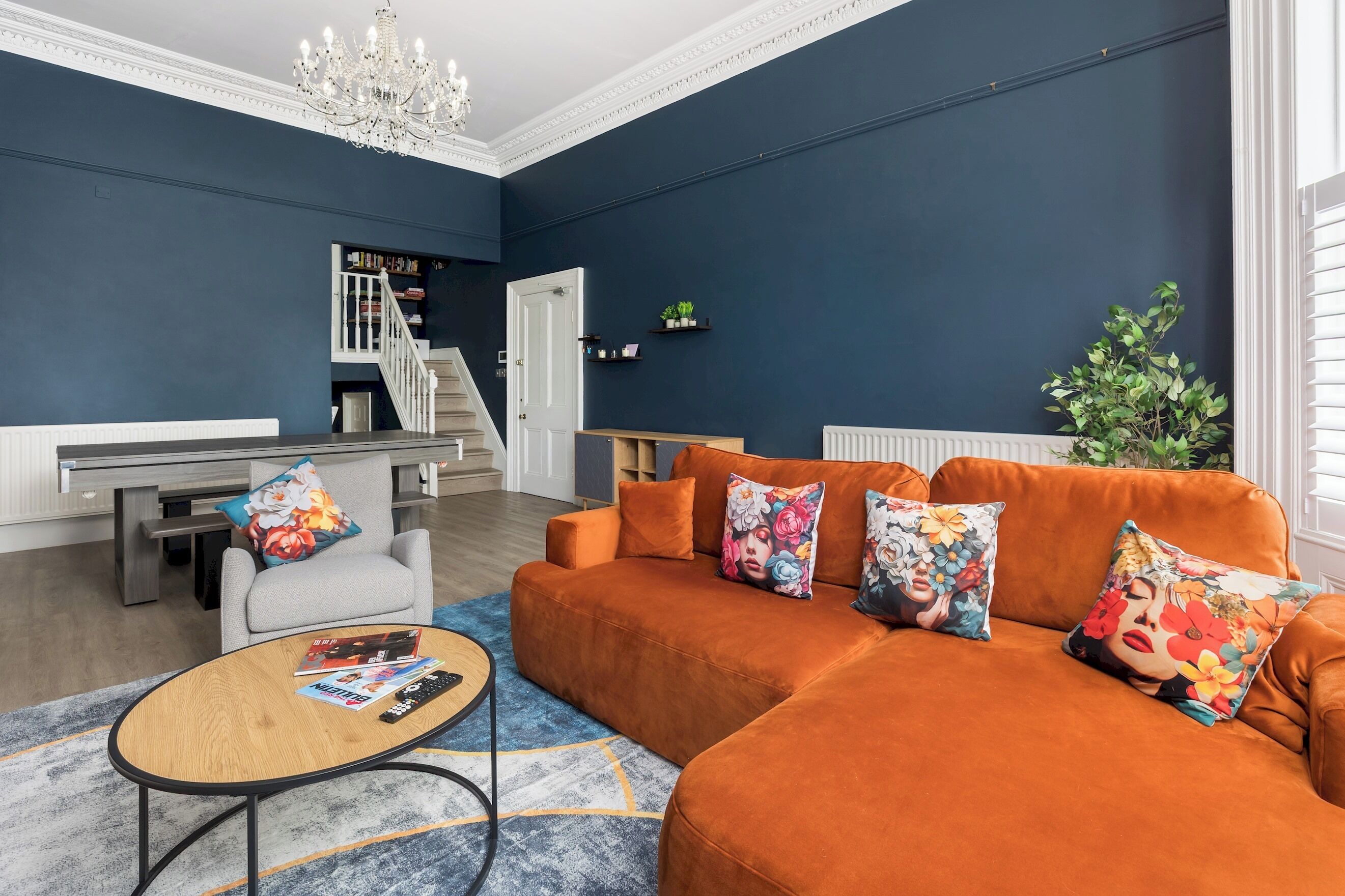 A living room with a sofa, armchairs, a coffee table, and a staircase leading to a balcony.