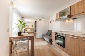 Eine moderne Küche mit Holzschränken, einem eingebauten Ofen und einem Essbereich mit Tisch und Stühlen.