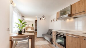 Een moderne keuken met houten kastjes, een inbouwoven en een eethoek met een tafel en stoelen.