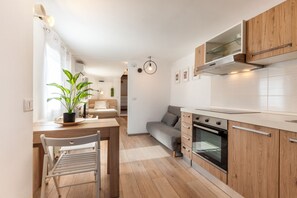 Eine moderne Küche mit Holzschränken, einem eingebauten Ofen und einem Essbereich mit Tisch und Stühlen.