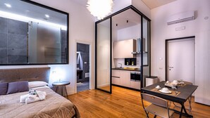 A modern hotel room with a bed, a dining table, a kitchen area, and a large mirror. - GuestHost - Spacious and charming 50 square meters studio apartment, perfect for three people, located on the first floor of a building (NO elevator).The property is located in the central area of ​​Salerno (limited traffic zone), a neighborhood well (Salerno)