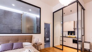 A modern hotel room with a large bed, a glass-enclosed bathroom, and a kitchenette. - GuestHost - Spacious and charming 50 square meters studio apartment, perfect for three people, located on the first floor of a building (NO elevator).The property is located in the central area of ​​Salerno (limited traffic zone), a neighborhood well (Salerno)