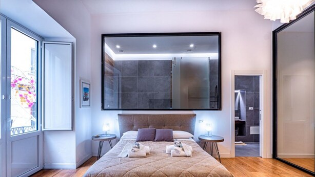 A modern hotel room with a large bed, a large mirror, and a view of the bathroom. - GuestHost - Spacious and charming 50 square meters studio apartment, perfect for three people, located on the first floor of a building (NO elevator).The property is located in the central area of ​​Salerno (limited traffic zone), a neighborhood well (Salerno)