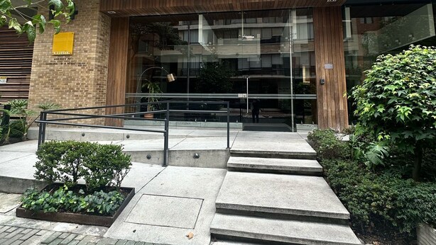 Een modern gebouw met een bakstenen gevel, grote ramen en een houten overkapping.