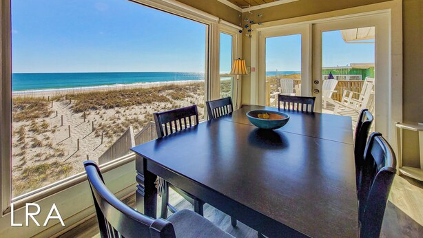 Zona pranzo con vista sulla spiaggia, soffitto in legno e tavolo con sedie.