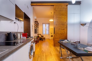A modern kitchen with a built-in dishwasher, a coffee machine, and a dining area with a table set for two.