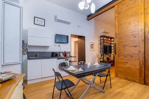 A compact kitchen with a dining area, a washing machine, and a TV mounted on the wall. - GuestHost - This elegant and modern 60 square meters apartment, perfect for four people, is located on the first floor of a building (no elevator).The property is located in the central area of ​​Salerno (limited traffic zone), a neighborhood well-se (Salerno)