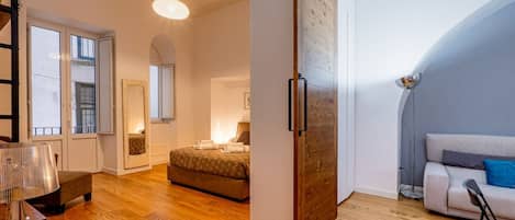 Un dormitorio con cama, mesita de noche, lámpara y ventana.