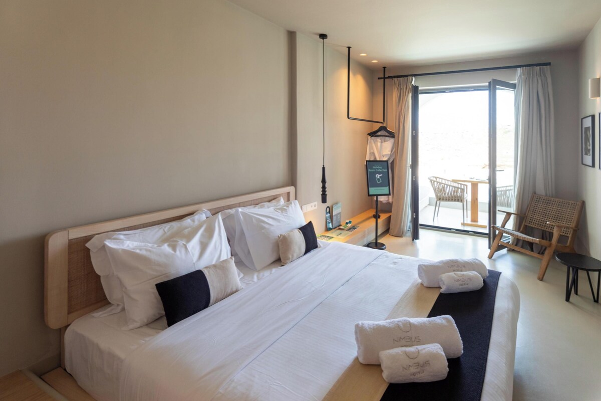 Een hotelkamer met een groot bed, een bureau met een computer, een stoel en uitzicht op de omgeving.