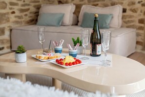 Une table ronde avec une bouteille de vin, deux verres, une assiette de nourriture et une petite plante.