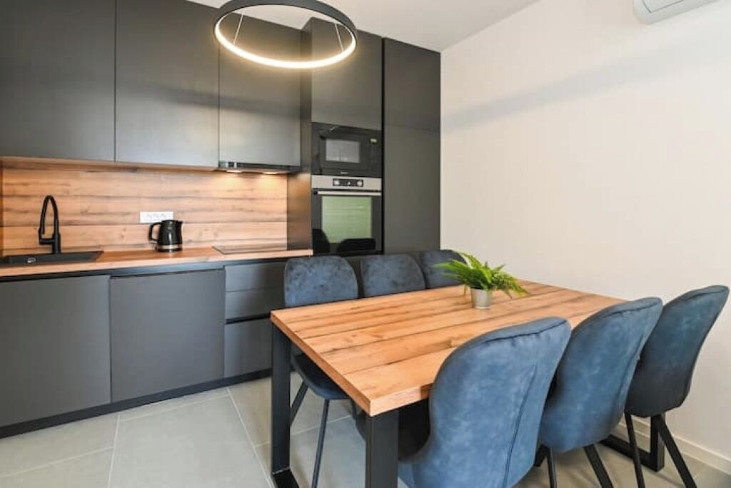A modern kitchen with grey cabinets, a wooden countertop, and a built-in oven.
