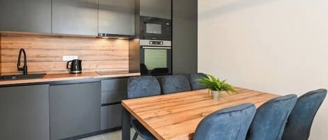 A modern kitchen with grey cabinets, a wooden countertop, and a built-in oven.