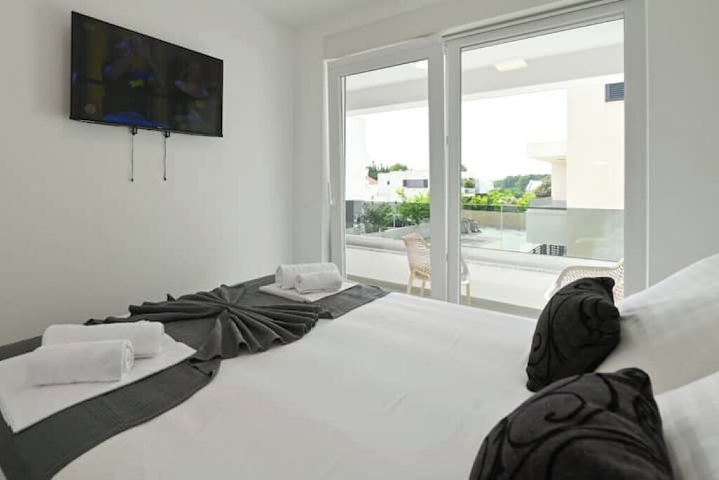 Une chambre d’hôtel équipée d’un lit, d’un téléviseur à écran plat fixé au mur et d’un balcon avec une porte vitrée.