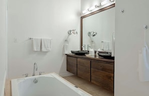 A modern bathroom with a bathtub, a large mirror, and a wooden vanity. - Tamarind Villa, Montpelier Nevis (Charlestown)