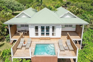 A two-story house with a pool, deck chairs, and a patio area.