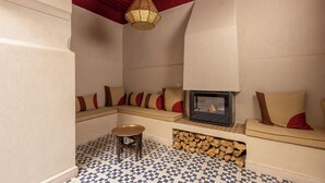 A cozy seating area with a patterned floor, a small table, and a fireplace. - Riad Cedrat (Marrakech)