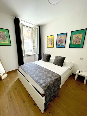 A bedroom with a bed, a window with curtains, and three framed pictures on the wall. - CameliaHouse Modern two-room apartment -45 m² 4 beds (Roma)