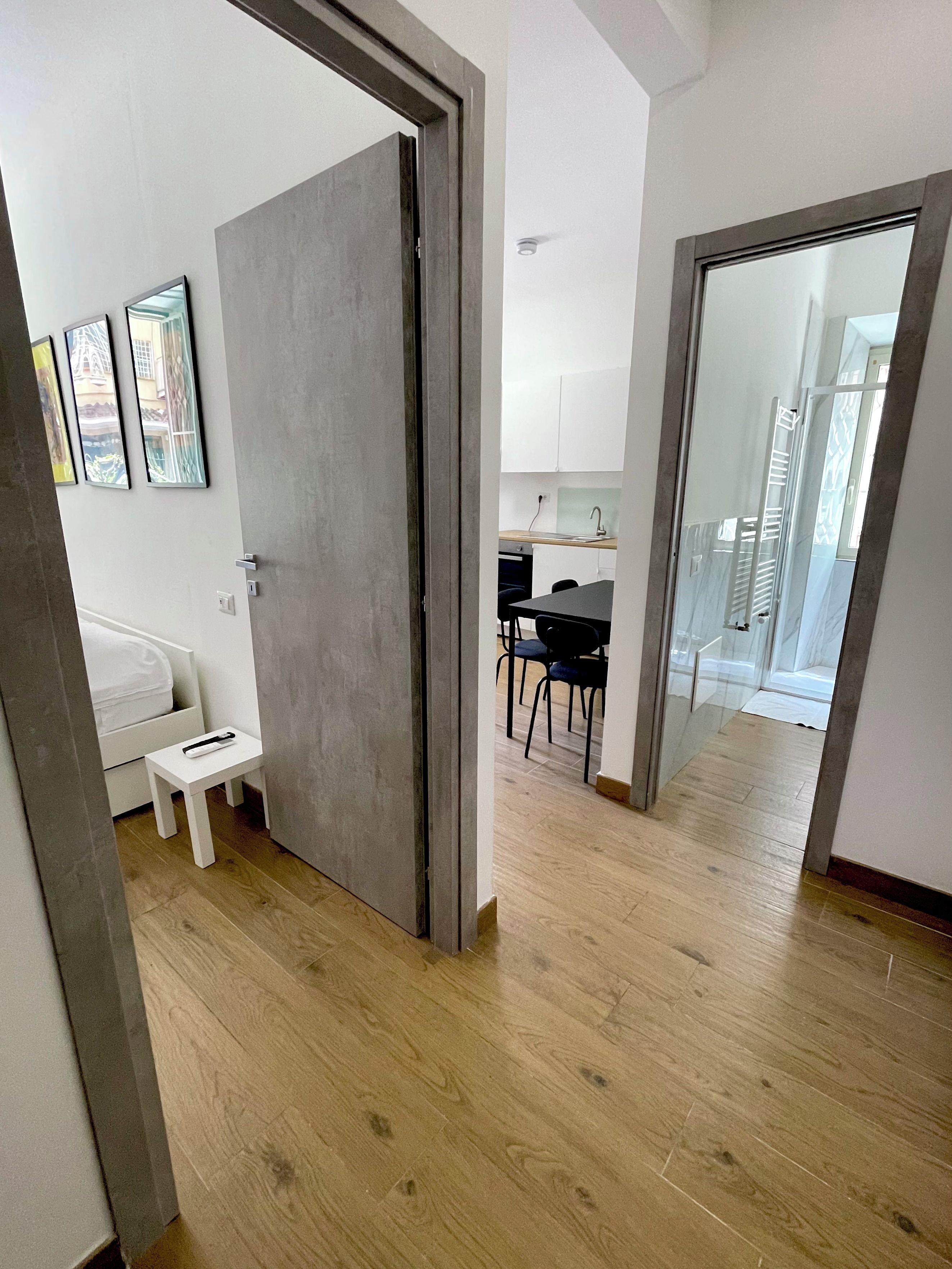 Un interno moderno con pavimento in legno, un letto, un tavolino e un angolo ristoro con sedie.
