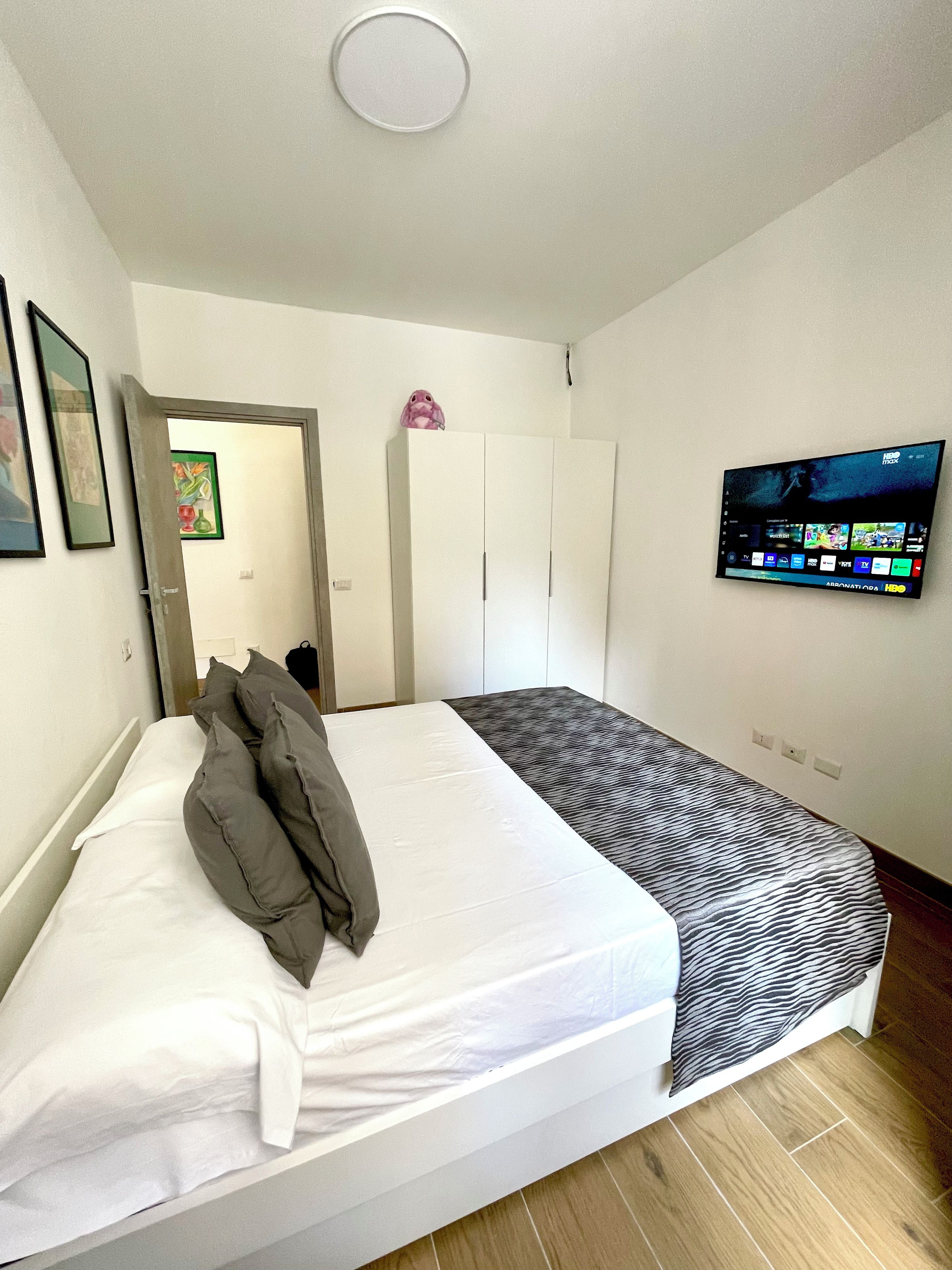 Une chambre à coucher avec un lit, un téléviseur fixé au mur et une armoire.