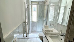 Ein modernes Badezimmer mit Duschkabine aus Glas, einem weißen Waschbecken und einem großen Spiegel.