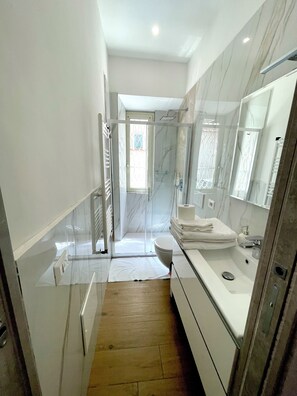 A modern bathroom with a glass shower enclosure, a white sink, and a large mirror. - CameliaHouse Modern two-room apartment -45 m² 4 beds (Roma)