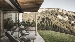 Une terrasse en bois avec des sièges extérieurs, offrant une vue sur un paysage montagneux.