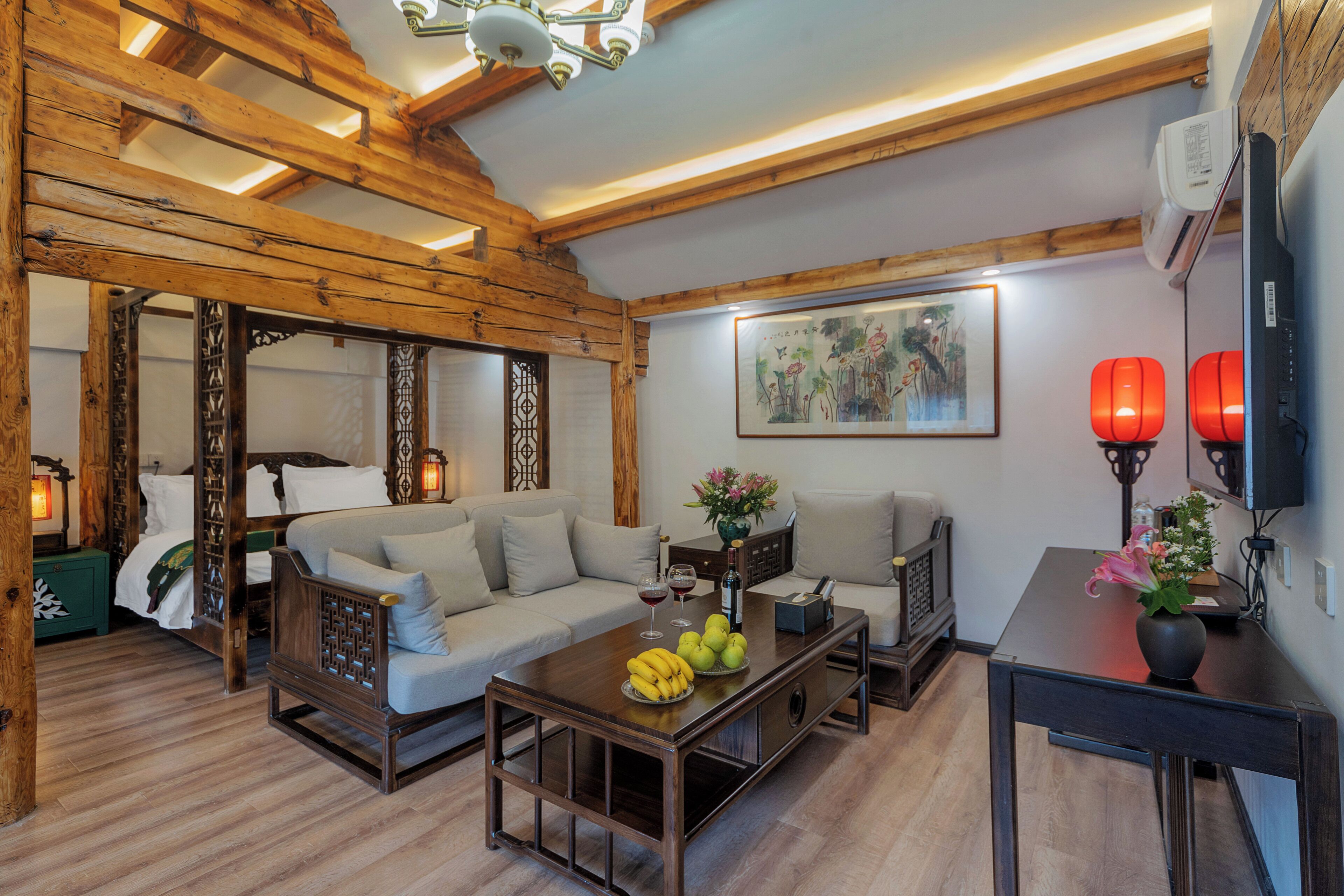 A traditional-style living room with a wooden ceiling, a sofa, a coffee table with fruit, and a painting on the wall.