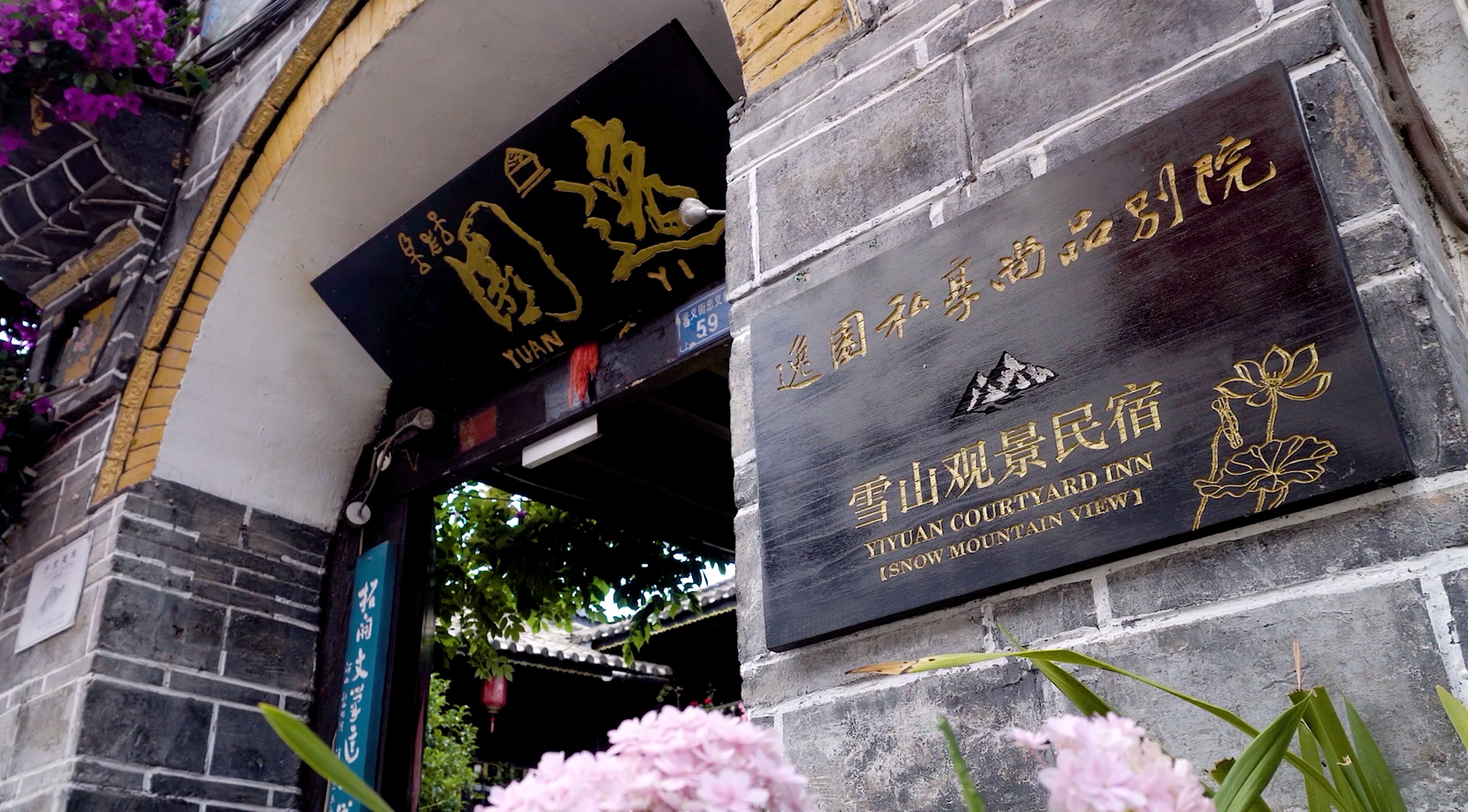 A stone building with a plaque that reads "YIYUAN COURTYARD INN" and "ISNOW MOUNTAIN VIEW".