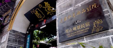A stone building with a plaque that reads "YIYUAN COURTYARD INN" and "ISNOW MOUNTAIN VIEW".