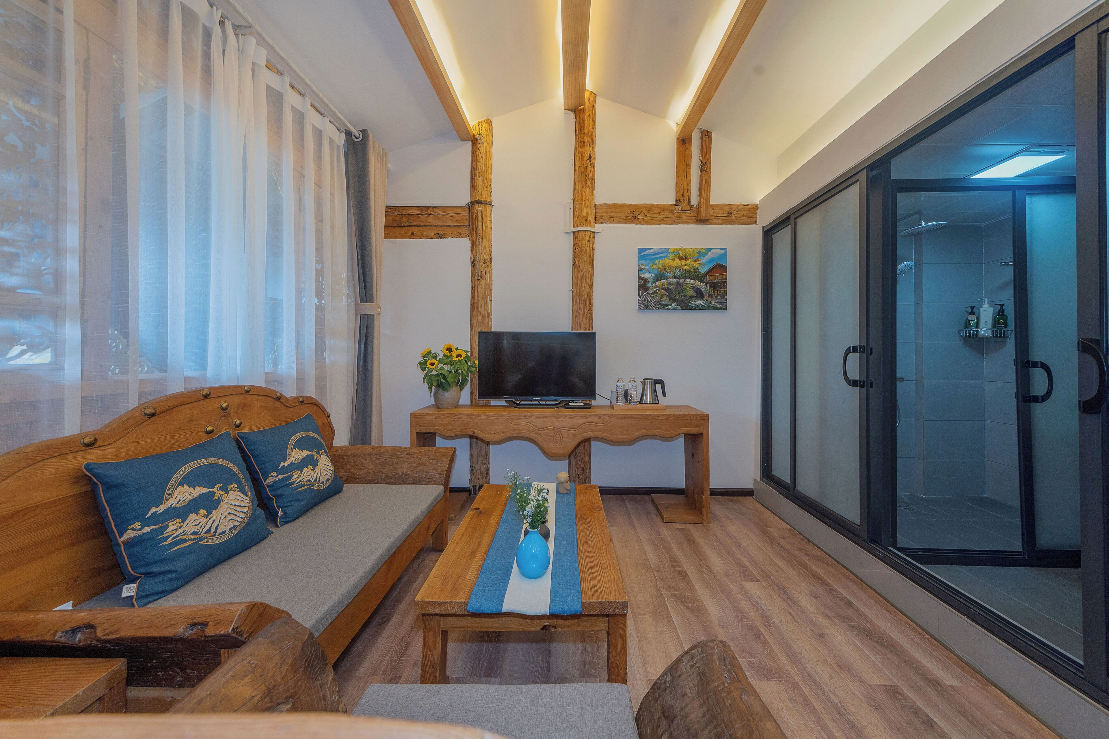 A modern living room with a wooden sofa, a TV, and a glass shower enclosure.