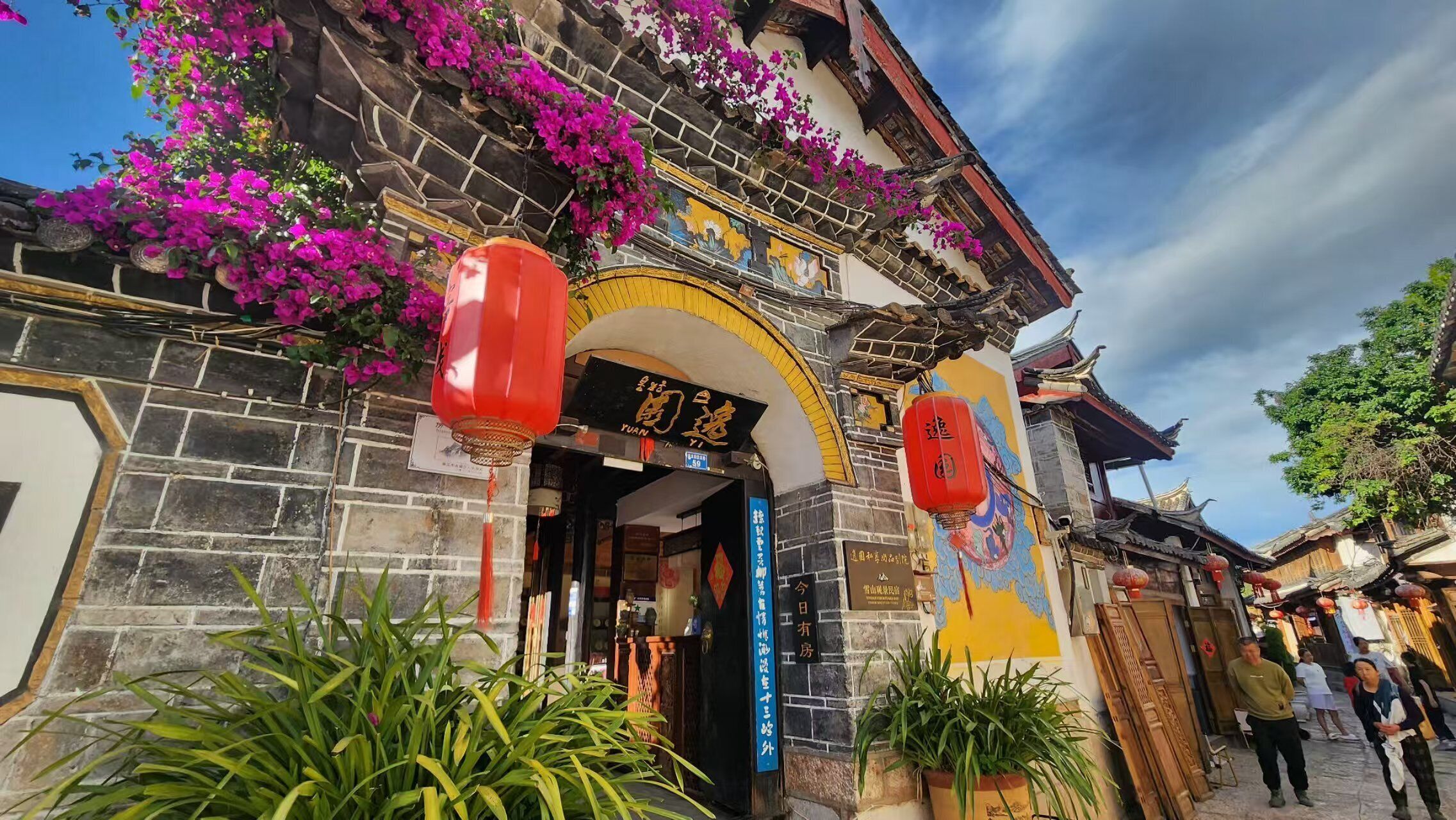 Un edificio tradicional con fachada de piedra, un mural colorido y faroles rojos colgantes.