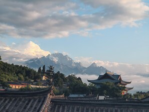 Traditional architecture with tiered roofs, a mountainous backdrop, and a clear sky.