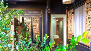 A traditional Japanese-style interior with a wooden door, intricate wall carvings, and a modern bathroom visible through an open doorway. - Yiyuan Snow Mountain View Historical Naxi House - Lijiang Old Town Mufu branch (Lijiang)