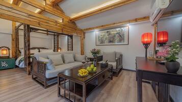 Un salón de estilo tradicional con techo de madera, un sofá, una mesa de centro con fruta y un aire acondicionado montado en la pared.