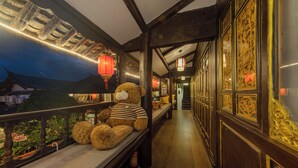 Een gang met houten balken, een bankje met een teddybeer en traditionele lantaarns.