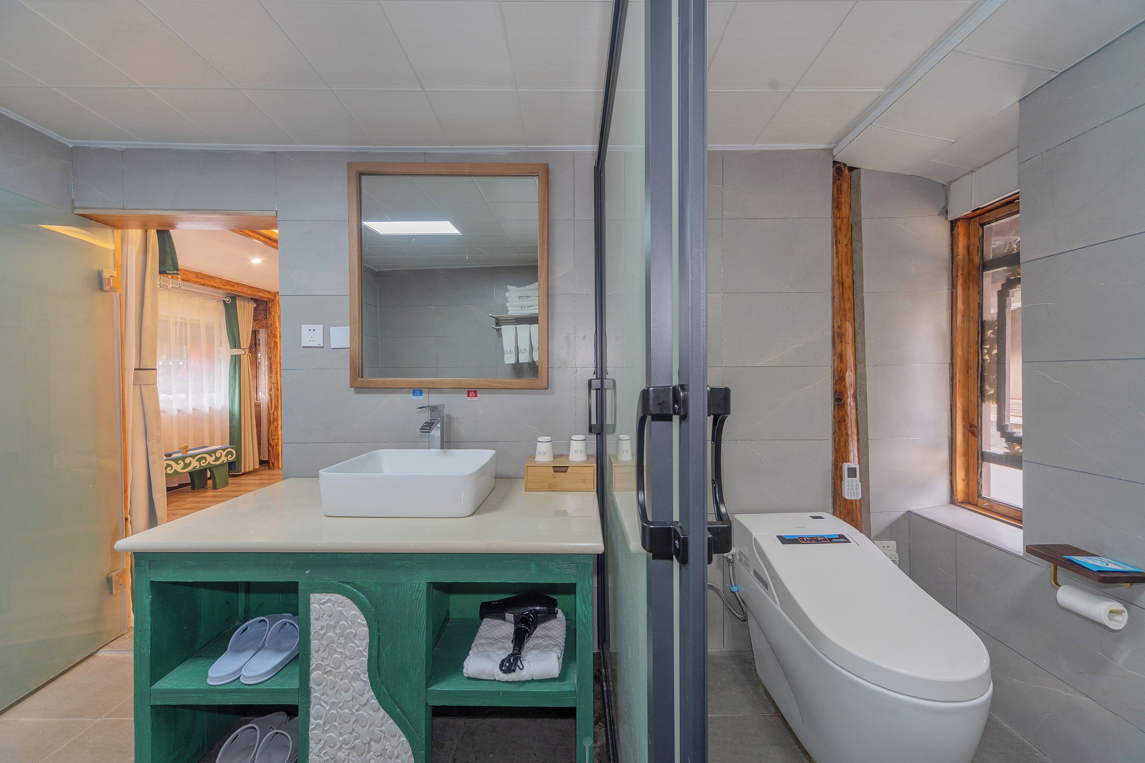 A modern bathroom with a white sink, a large mirror, a toilet, and a shower area.