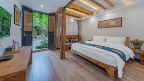 Een slaapkamer met een houten bed, een bureau en een raam met uitzicht op groen.