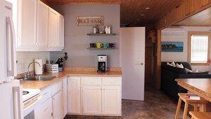 A kitchen with white cabinets, a coffee maker, and a sign that reads "BEACH HOUSE". - Ocean View Cottage, With Access To Tracadie Bay-Minutes From Blooming Point (Mount Stewart)