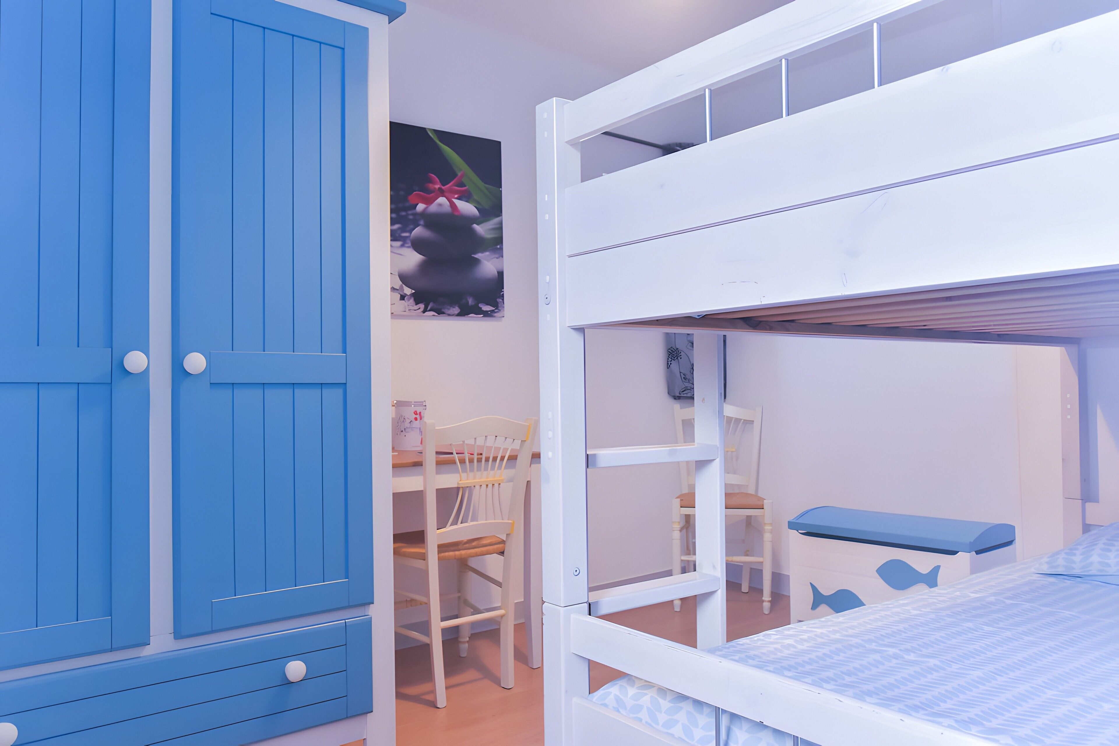 Une chambre d’enfant avec des lits superposés, un bureau et une chaise.